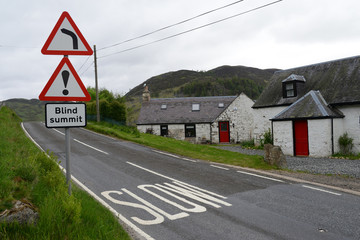 Panneaux indiquant un virage et un danger sur une route des Highlands en Ecosse