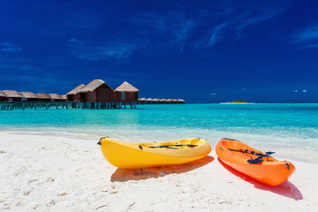 Yellow and orangel kayaks on the tropical beach with vilas