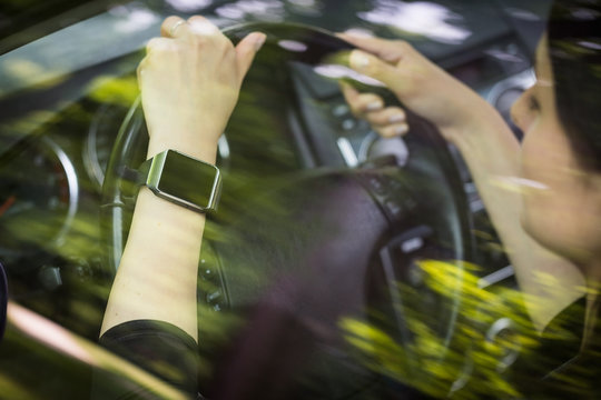 A woman uses smartwatch in the car.