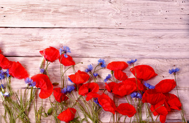 Fototapeta na wymiar Poppies and cornflowers on white wooden background