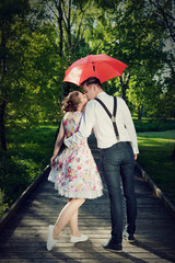 Young romantic couple in love flirting in rain. Red umbrella