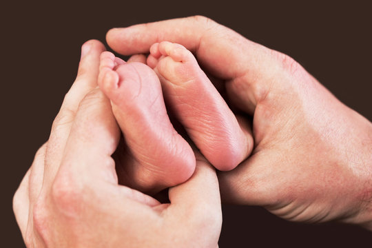 Newborn baby feet in father hands
