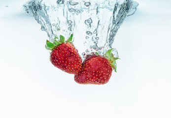 Fresh strawberry dropped into water with splash