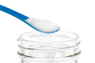 Blue Spoon Pouring Salt on White background