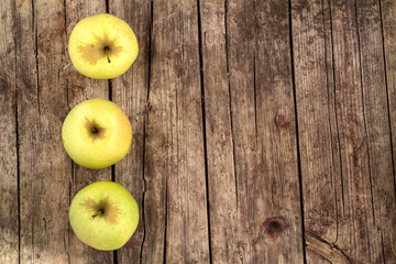 Three green apples on a wooden background