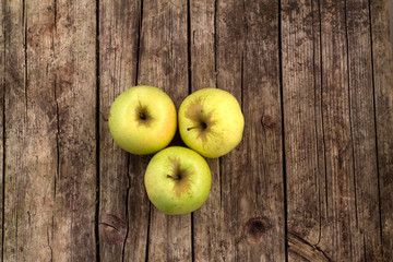 Three green apples on a wooden background