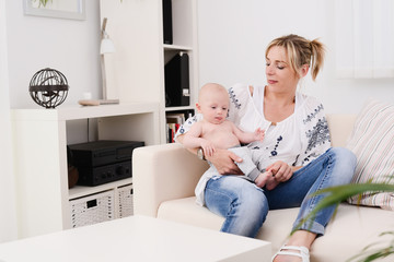 Obraz premium young woman at home playing and taking care of lovely new born baby boy