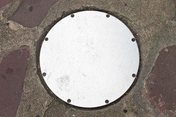 Circle Metal drain cap on sidewalk