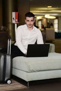 handsome young business man traveler working with laptop computer in a hotel lobby
