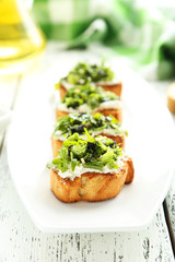 Tasty fresh bruschetta on plate on white wooden background