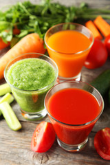 Fresh tomato, carrot and cucumber juice on grey wooden background