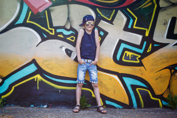 Obraz na płótnie Canvas Fashionable little boy in sunglasses and cap.Graffiti background