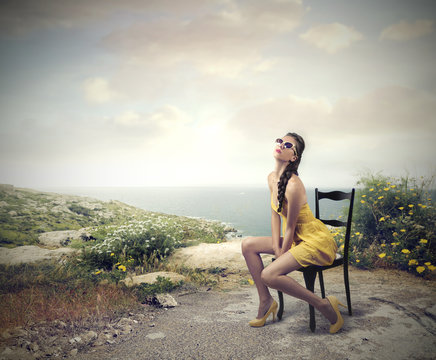 Fashionable girl sitting on a chair by the seaside
