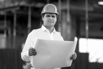 Black and white portrait of foreman posing with documents and bl