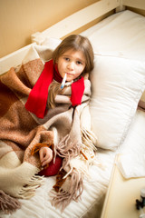 Fototapeta premium sick girl lying in bed with teddy bear and measuring temperature