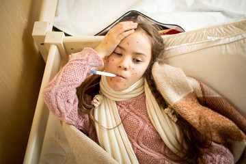 sick girl with chickenpox lying in bed and measuring temperature - obrazy, fototapety, plakaty