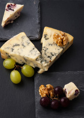 Different types of cheeses on black board.