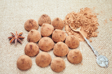 Chocolate truffles candies on a background of burlap bag texture with anise flowers, selective focus and vintage old style for chocolate day