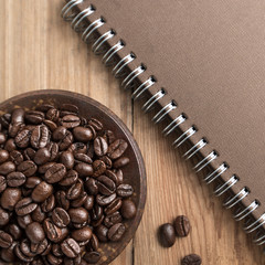 Diary and the coffee concept background. Coffee beans in the plate with a notebook.