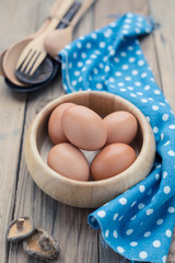 The eggs in the wooden bowl on Kitchen table. The cooking background.