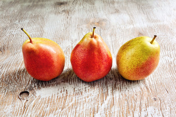 Three ripe pears on rustic wooden background, summer harvest, selective focus, toned image
