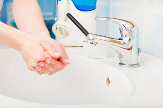 Woman washing hands under flowing tap water