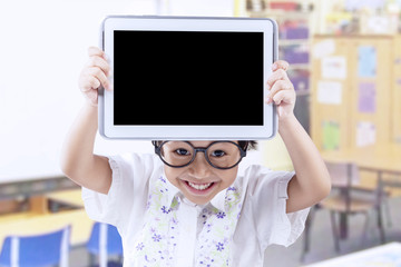 Adorable little child showing tablet at school