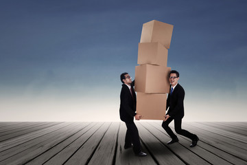 Two businessman lifting many boxes outdoor