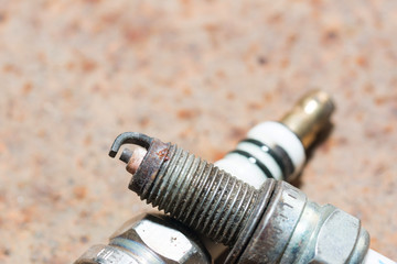 Used and new sparkplug, isolated Rusty iron background
