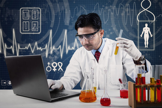 Scientist with laptop and chemical glassware