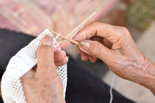 The old woman's hands are woven fishing equipment.