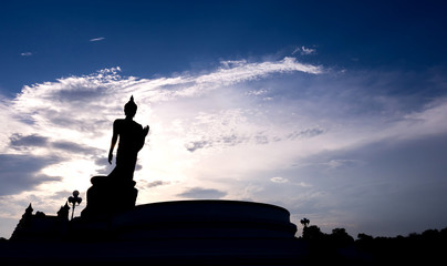 Silhouette walking buddha statue with blue sky