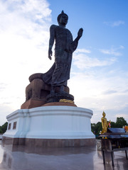 Walking buddha bronze statue in park