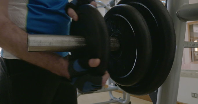 Sportsman putting disk weight on the barbell in gym