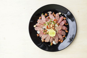 Thai sour pork sausage salad in black plate 
