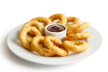 Heap of deep fried onion or calamari rings with barbecue dip on