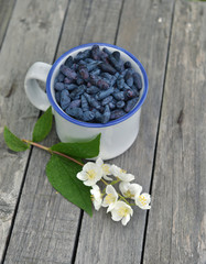 Cup with honeyberry and jasmine flowers on old planks