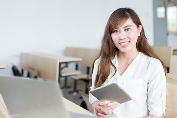 Asian beautiful female student study with tablet in classroom