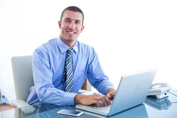Smiling businessman using his laptop