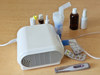 Fototapeta na wymiar Treatment of allergy, asthma and pneumonia with a nebulizer. Tablets, drops, medicine and a thermometer