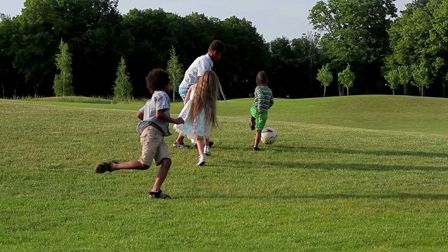 Kids are playing with a ball on evening glade.