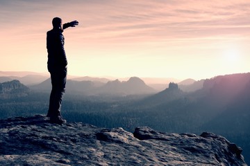 Slim tourist on the sharp peak of rock in rock empires park  is watching over the misty and foggy...