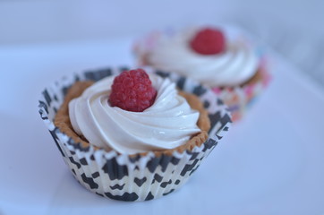 Beautiful cupcakes with cream top and raspberries