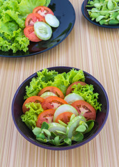mix vegetable salad on wooden background, tomato, cucumber, lettuce, sunflower sprouts