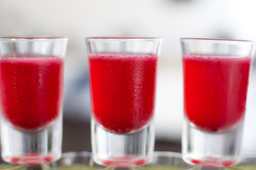Beautiful line of different colored alcohol mojito cocktails with mint on a open air party, tequila, martini, vodka, and others on decorated catering bouquet table on open air event party.