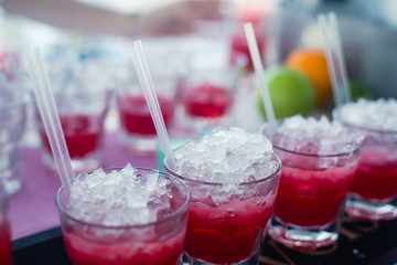 Beautiful line of different colored alcohol mojito cocktails with mint on a open air party, tequila, martini, vodka, and others on decorated catering bouquet table on open air event party.