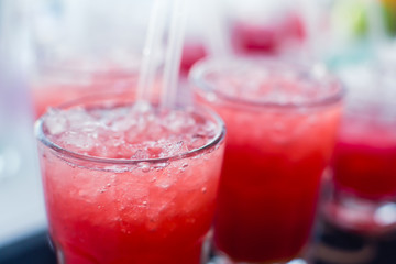 Beautiful line of different colored alcohol mojito cocktails with mint on a open air party, tequila, martini, vodka, and others on decorated catering bouquet table on open air event party.