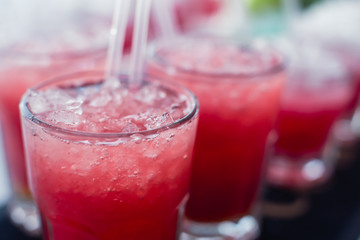 Beautiful line of different colored alcohol mojito cocktails with mint on a open air party, tequila, martini, vodka, and others on decorated catering bouquet table on open air event party.