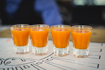Beautiful line of different colored alcohol mojito cocktails with mint on a open air party, tequila, martini, vodka, and others on decorated catering bouquet table on open air event party.