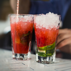 Beautiful line of different colored alcohol mojito cocktails with mint on a open air party, tequila, martini, vodka, and others on decorated catering bouquet table on open air event party.